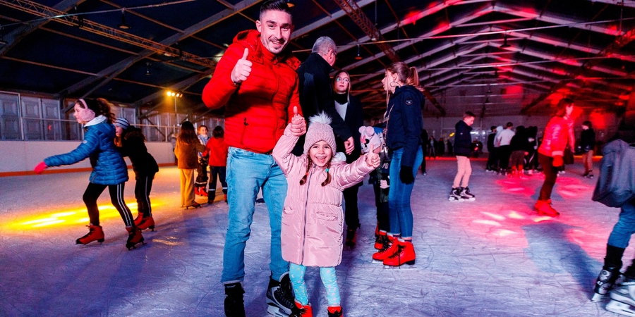 Een vader en dochter op schaatsen steken hun duim op Een vader en dochter op schaatsen steken hun duim op